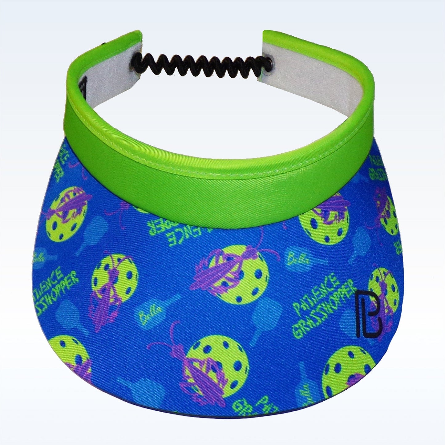 The Pickleball Bella PB Visor Patience Grasshopper features quick dry fabric, a moisture-wicking headband, a blue brim with paddles, yellow balls, pink grasshoppers, “PICKLE GRASSHOPPER,” “Bella,” and a black "B" logo on the right.
