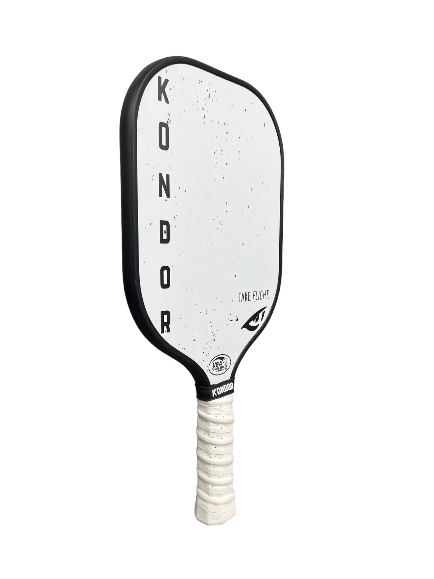 The ATTK 1.0 by KONDOR PICKLEBALL is a white paddle with a black border, "KONDOR" in vertical black letters, small black speckles, "TAKE FLIGHT" near the edge, and an elongated grip wrapped in white tape.