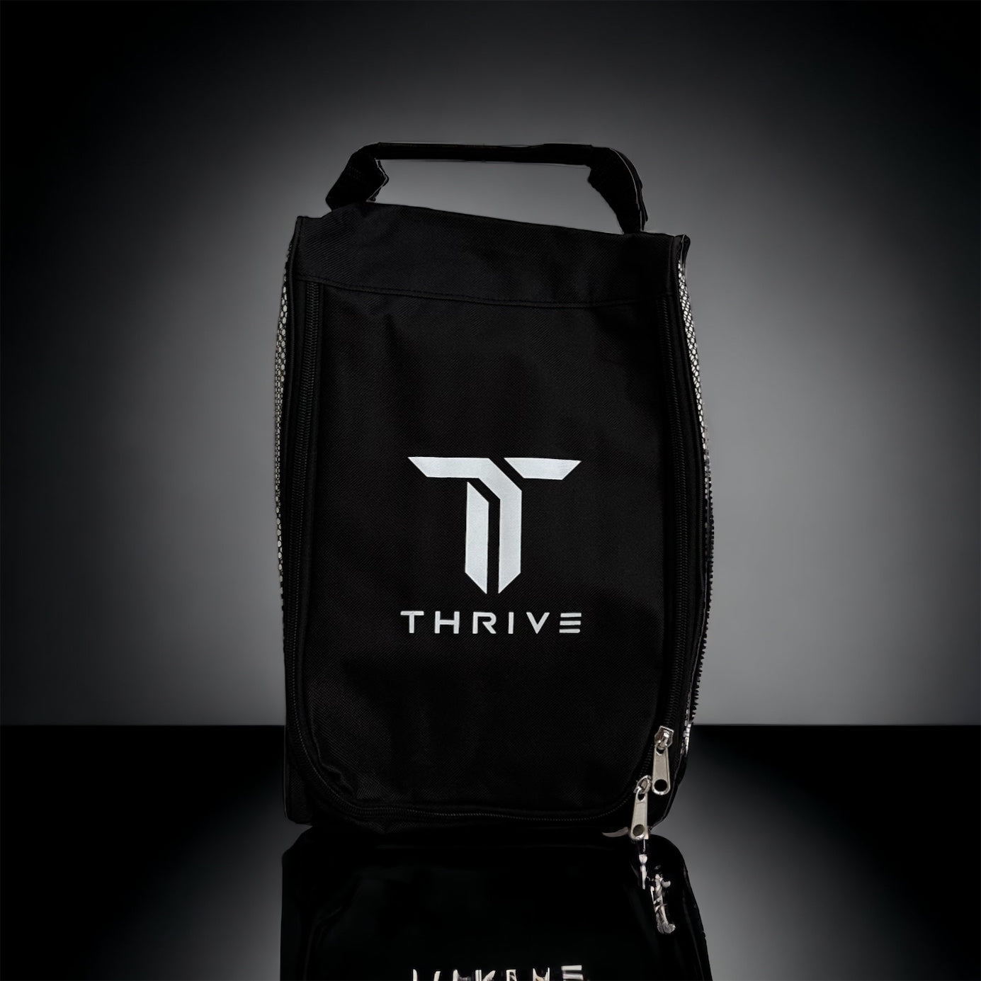 The Elite Pro Tour Bag w/shoe bag- BLACK by Thrive Pickleball stands upright on a reflective black surface, showcasing its bold white THRIVE logo and stylized T. Ideal for use as a pickleball tour bag with thermal-lined paddle compartments.