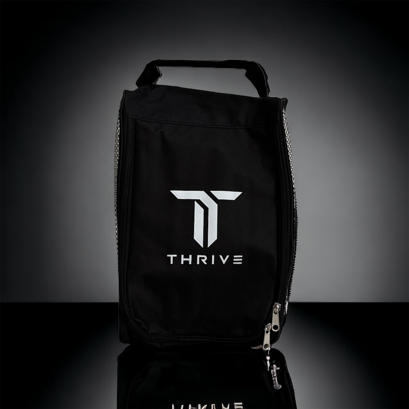 The THRIVE Shoe Bag (Size 12 and Under) by Thrive Pickleball stands upright on a black-to-gray gradient background, displaying a bold white T logo above "THRIVE" and featuring a top handle with the zipper partially open at the bottom right.