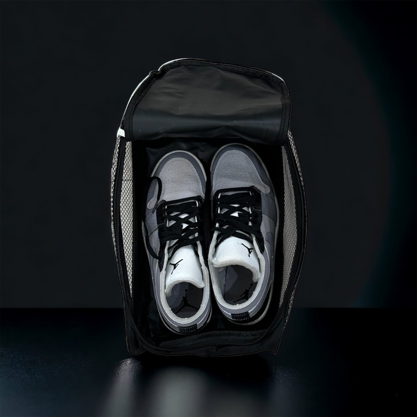 A pair of black and white sneakers with black laces are neatly packed side by side in the open THRIVE Shoe Bag (Size 12 and Under) by Thrive Pickleball, with mesh side panels, visible zipper, and top flap against a dark background.