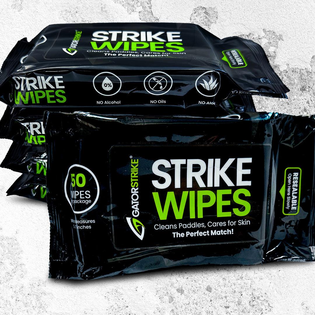 Three packs of GATORSTRIKE™ Paddle Wipes, in black packaging with green and white text, are stacked against a gray textured background. The front pack notes "50 alcohol-free, non-toxic wipes per package," resealable closure, and "No Oils" icons.