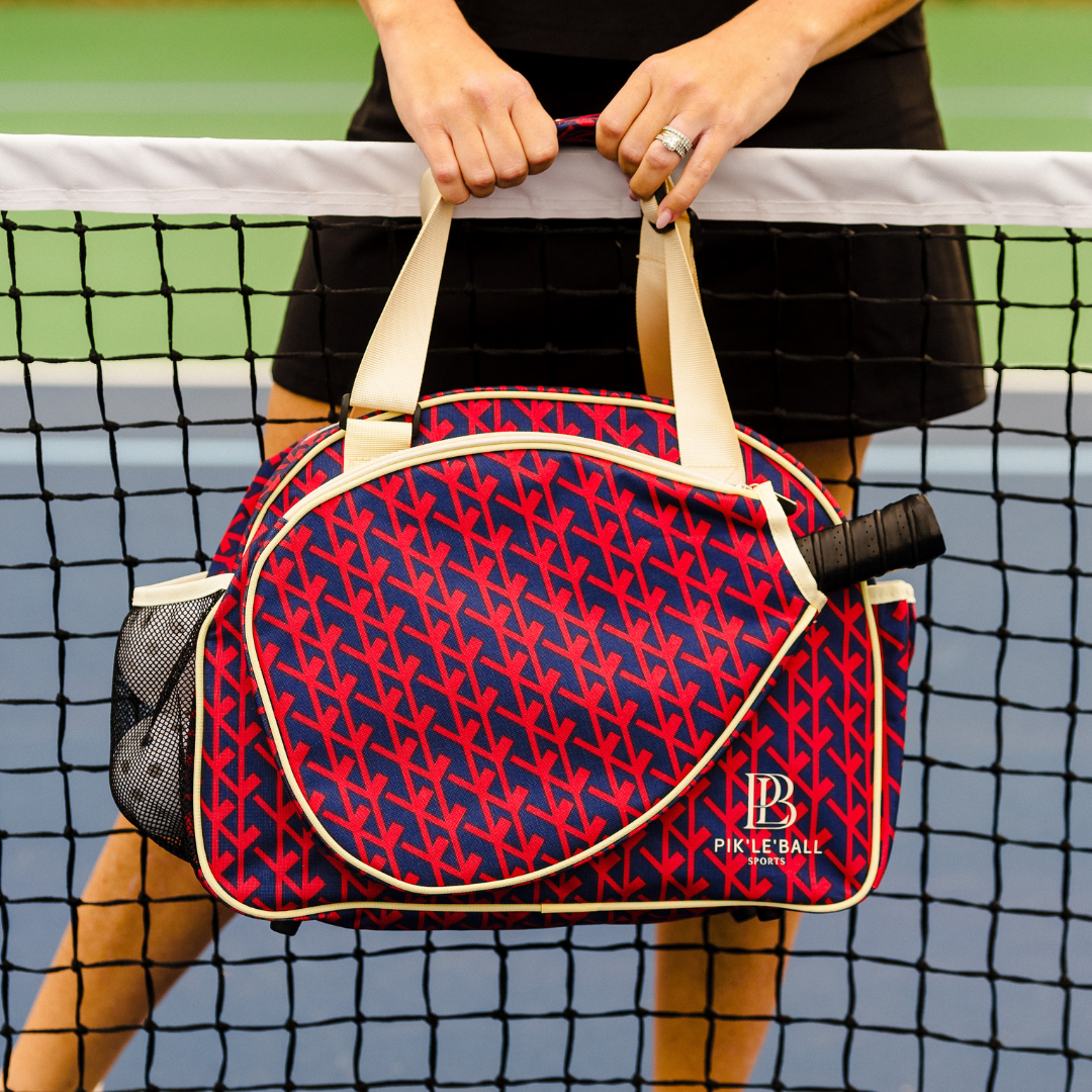 A woman holding the Court Couture Premium Women's Pickleball Bag by Pik'le'Ball Sports, featuring multiple compartments and a paddle sleeve.