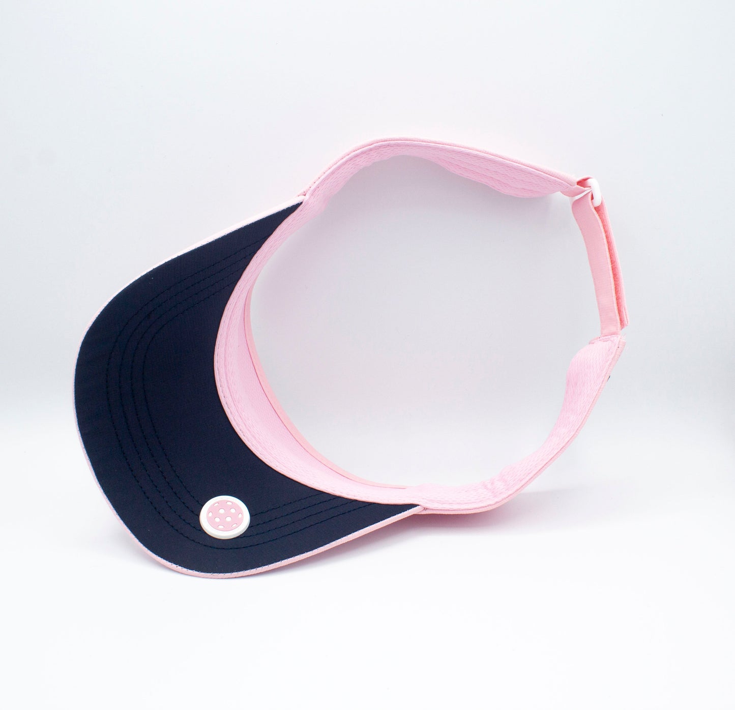 The Bodhi Performance ICON Visor is shown on a white background, featuring a black brim with a round white button, pink band, and an adjustable strap and buckle at the back.