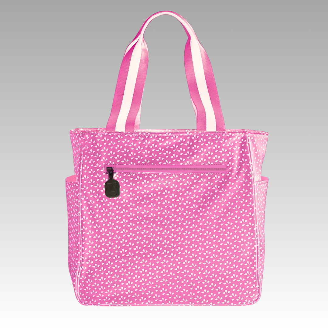 The Lulu Pickleball Tote by Playly Store features a pink design with white polka dots, striped pink-and-white handles, a front zipper pocket with black pull, and side pockets—your perfect pickleball accessory.