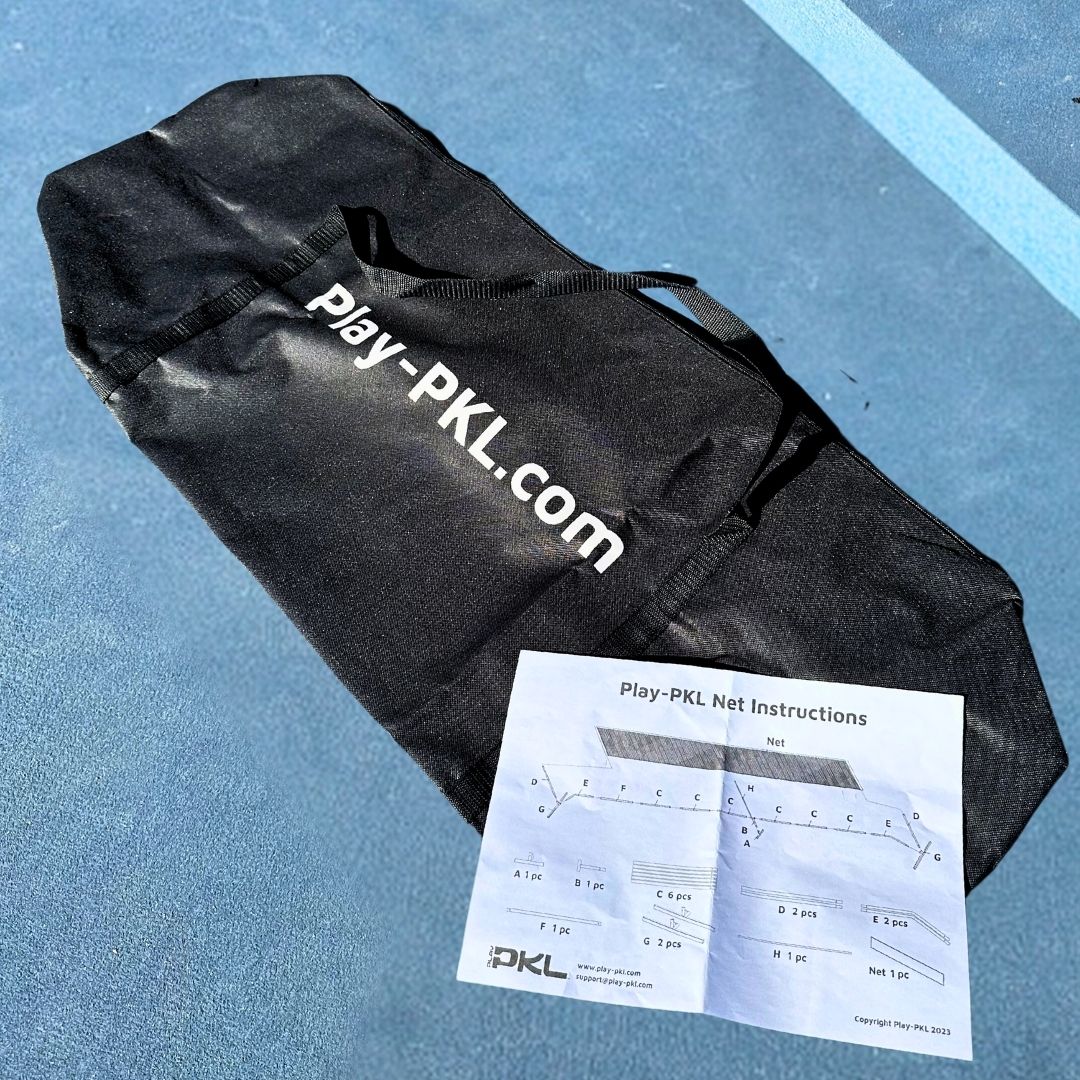A black Playly Store carrying bag with Play-PKL.com in white rests on a blue surface, next to Logo Portable Pickleball Net instructions featuring assembly diagrams. Bright sunlight casts shadows over the scene.