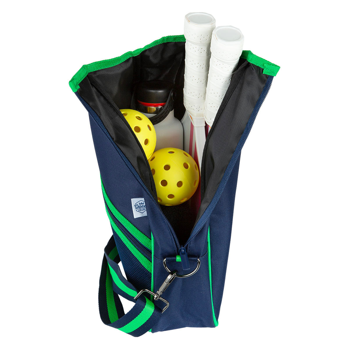 The Queen of the Court Essentials Pickleball Bag in navy with green trim features a striped shoulder strap, metal clip, and holds two yellow pickleballs, two paddles with white handles, and a water bottle.