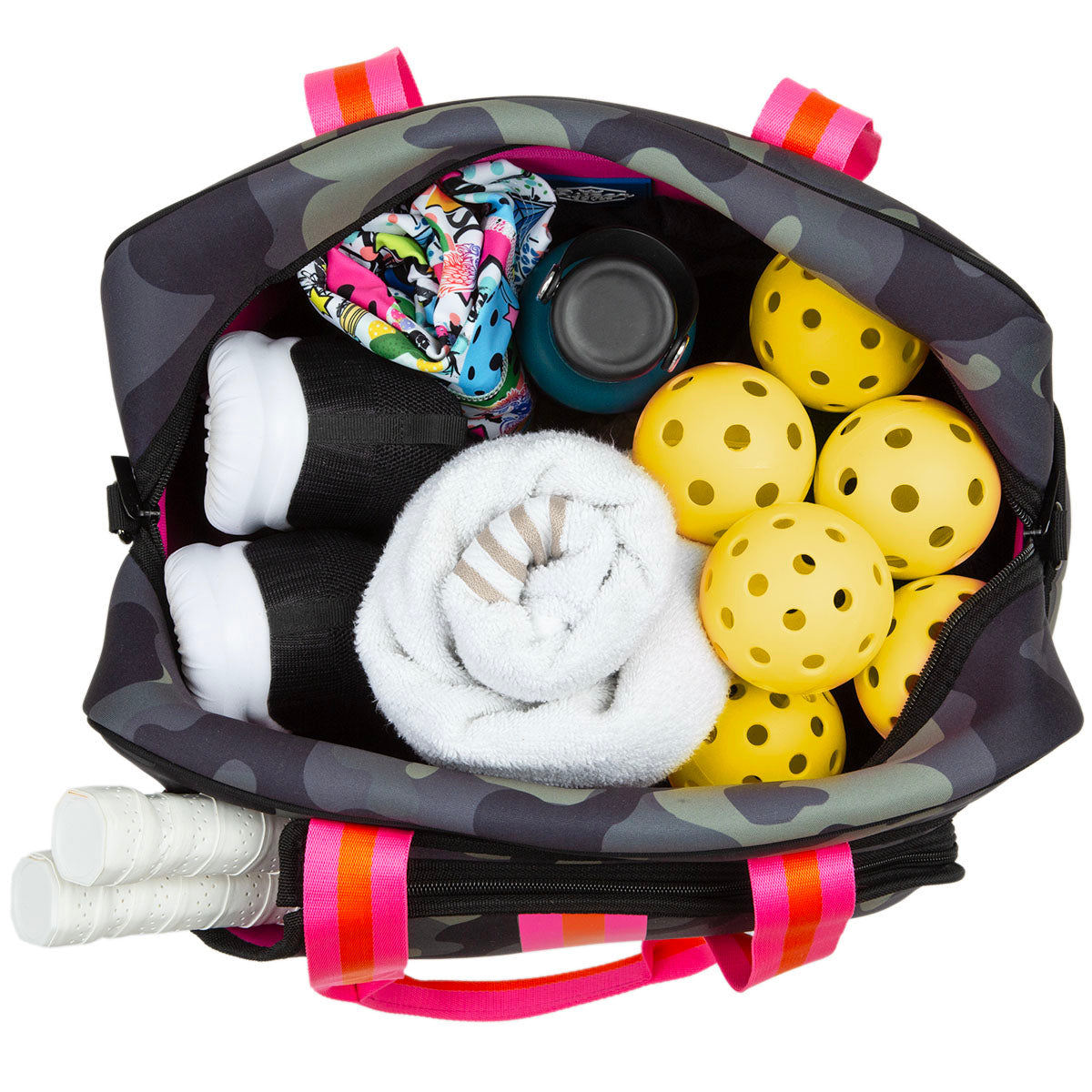 The Brooklyn Pickleball Bag by Queen of the Court, with pink handles and a dark patterned design, holds five yellow perforated balls, a white towel, black sneakers, a colorful item, blue water bottle, and three racquets in the side pocket.