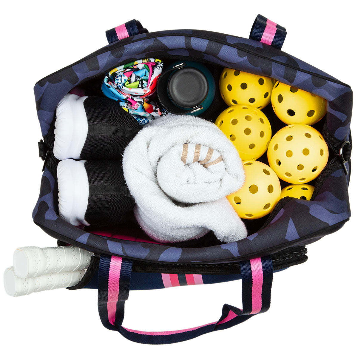 The Queen of the Court Brooklyn Pickleball Bag with pink-striped handles holds yellow pickleballs, a white towel, black shoes, a water bottle, patterned cloth, and spare racquet grips—all neatly arranged and viewed from above.
