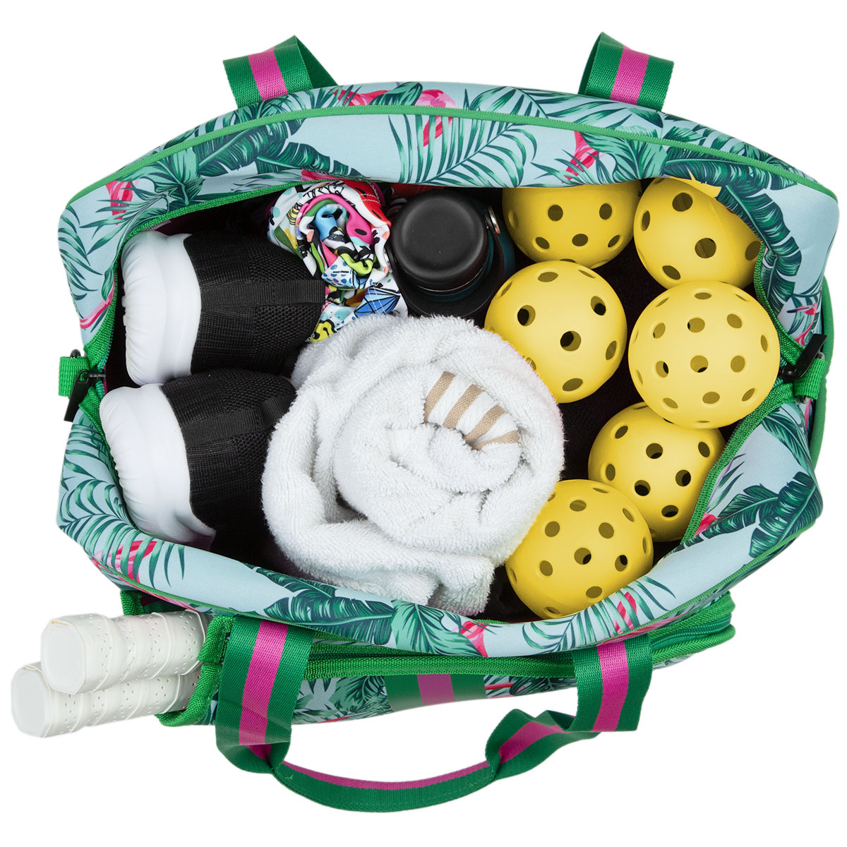A Queen of the Court Brooklyn Pickleball Bag with a tropical leaf pattern is open, showing yellow pickleballs, a rolled white towel, black shoes, a floral fabric piece, water bottle, and three racket handles in the outer pocket from an overhead view.