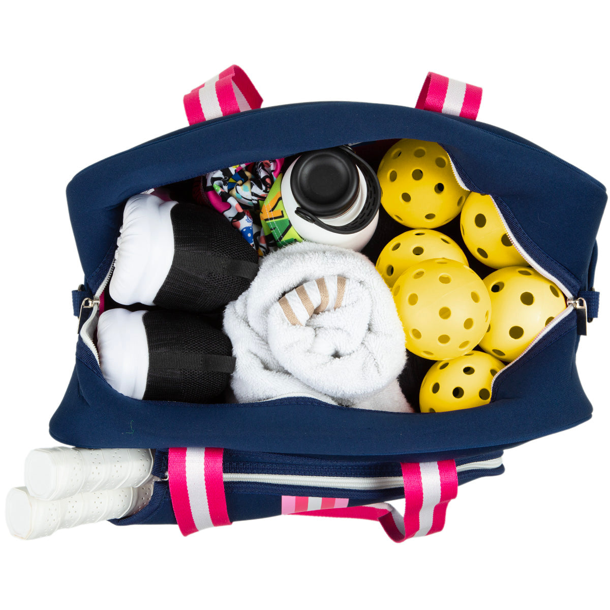 A navy blue Queen of the Court Brooklyn Pickleball Bag with pink handles is open, showing yellow pickleballs, a white towel, black and white sneakers, a water bottle, patterned clothing, and partially visible white racket handles.
