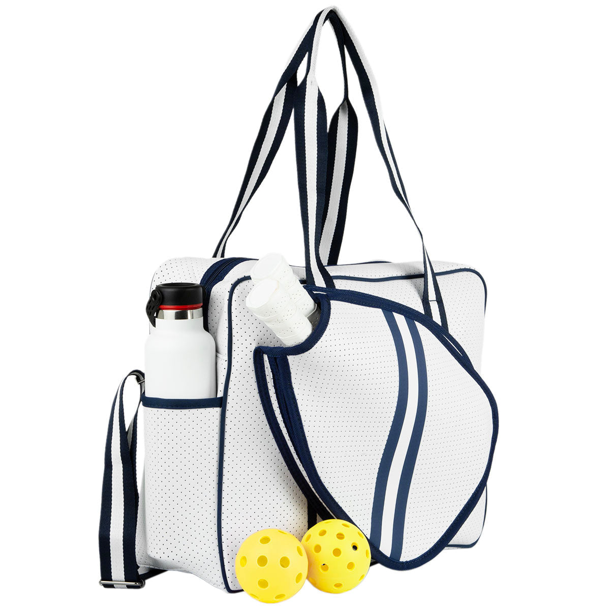 The Queen of the Court Brooklyn Pickleball Bag in white with navy trim offers a side pocket for water bottles or towels and a front paddle-shaped compartment. Two yellow perforated pickleballs sit in front of this stylish sports bag.