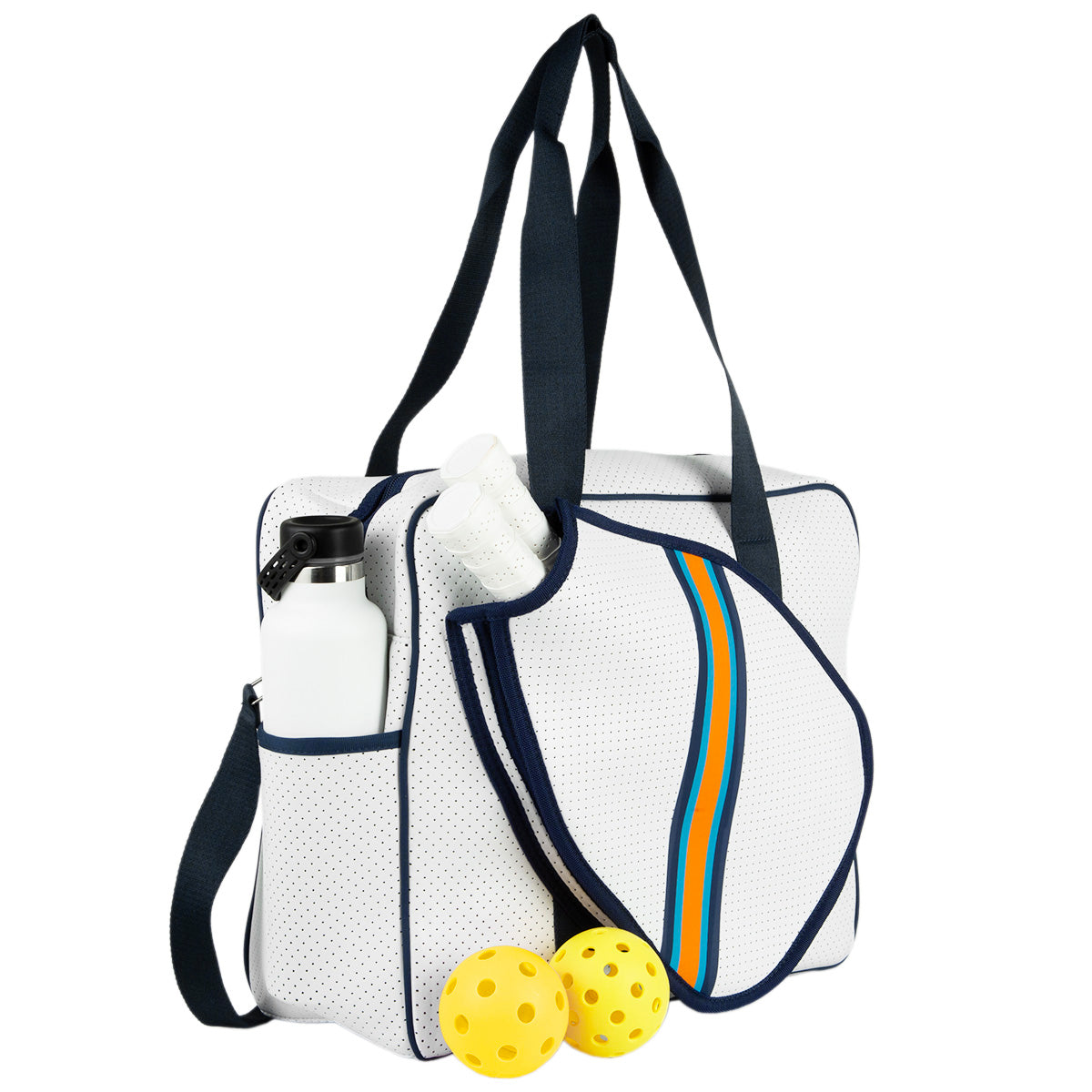The Queen of the Court Brooklyn Pickleball Bag in white has navy straps, orange and blue stripes, a paddle holder with two white paddles, a side pocket for a water bottle, and two yellow perforated balls are shown on the ground.
