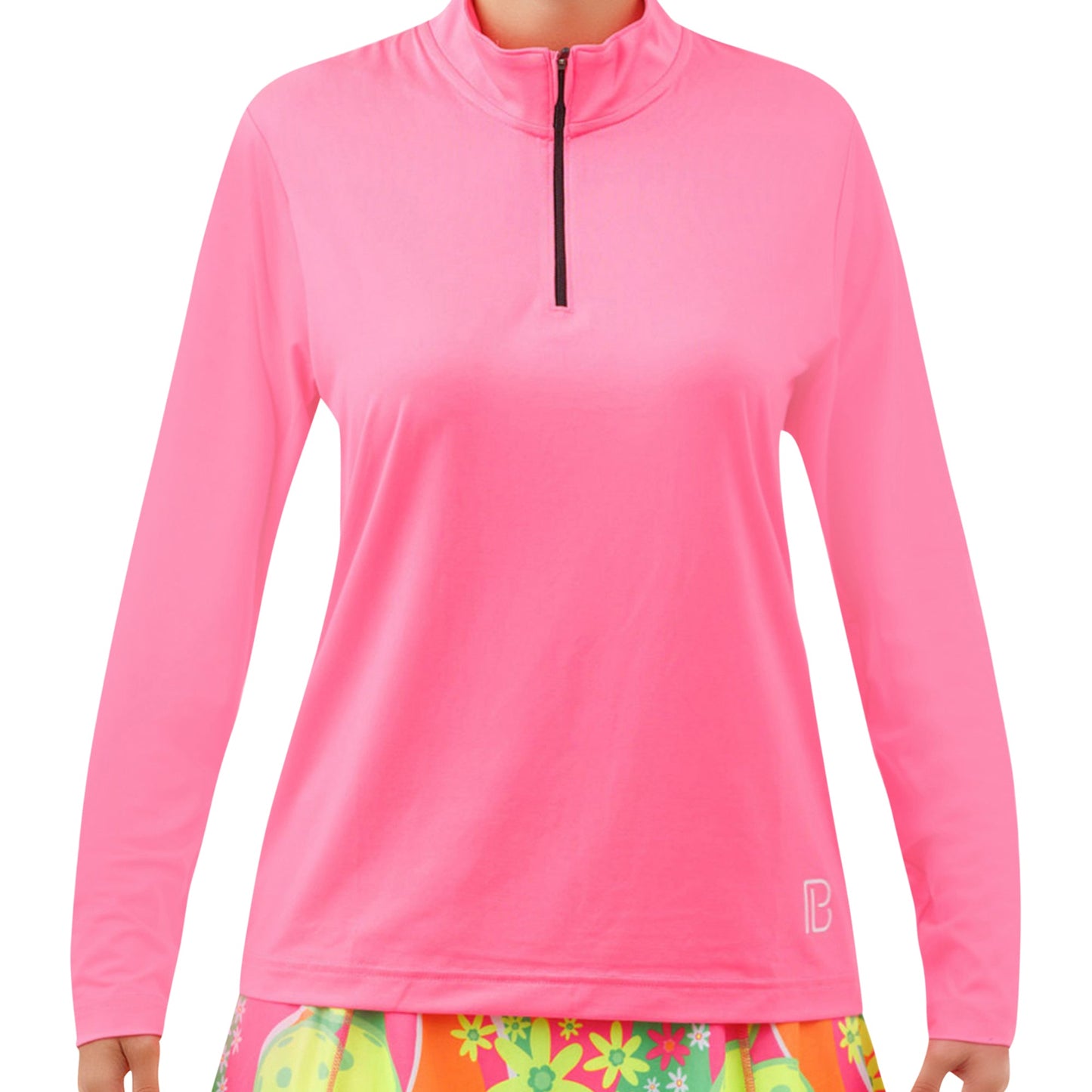 A person wears the Pickleball Bella PB 1/4 Zip Long Sleeve Hot Pink pullover with a small white logo on the hem, paired with a vibrant floral skirt in green, yellow, and pink.