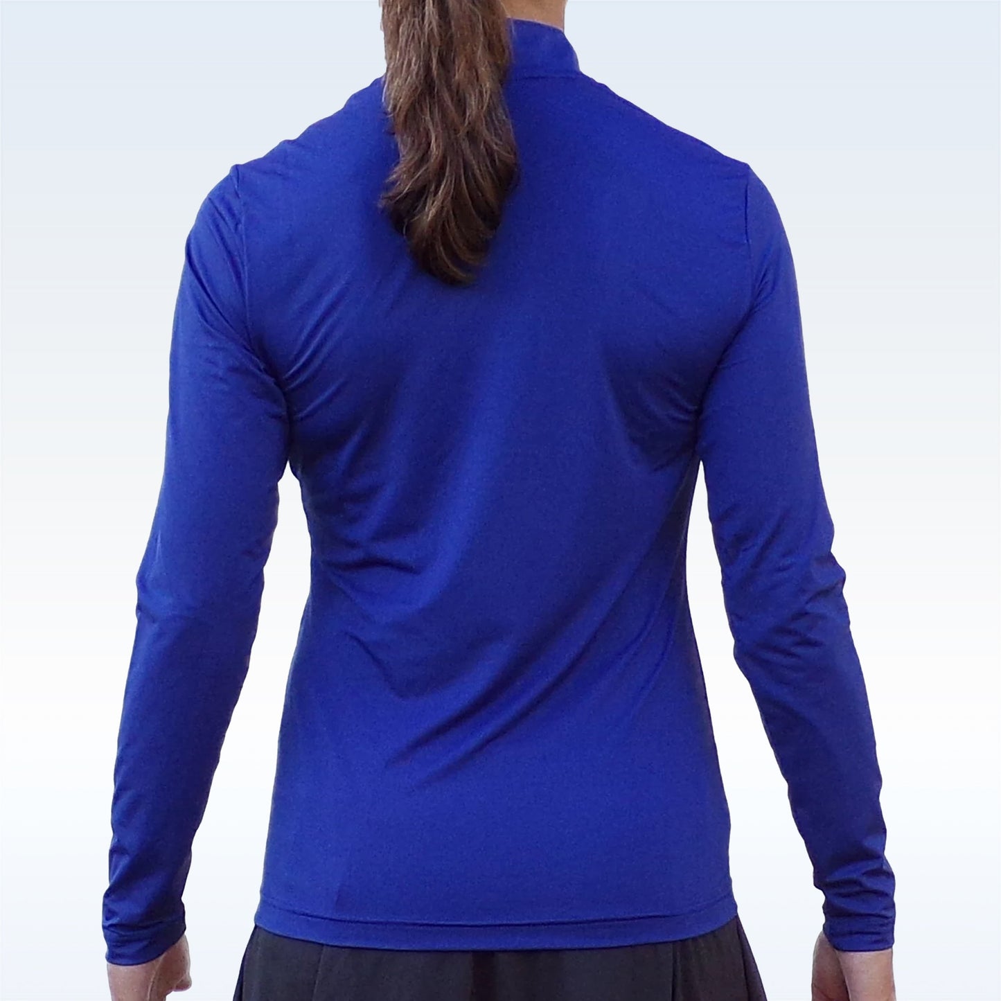 A person with long brown hair in a ponytail stands with arms at their sides, wearing Pickleball Bella’s PB 1/4 Zip Long Sleeve Navy—an SPF 50+ UV protection pullover—and dark pants, set against a pale gradient background.