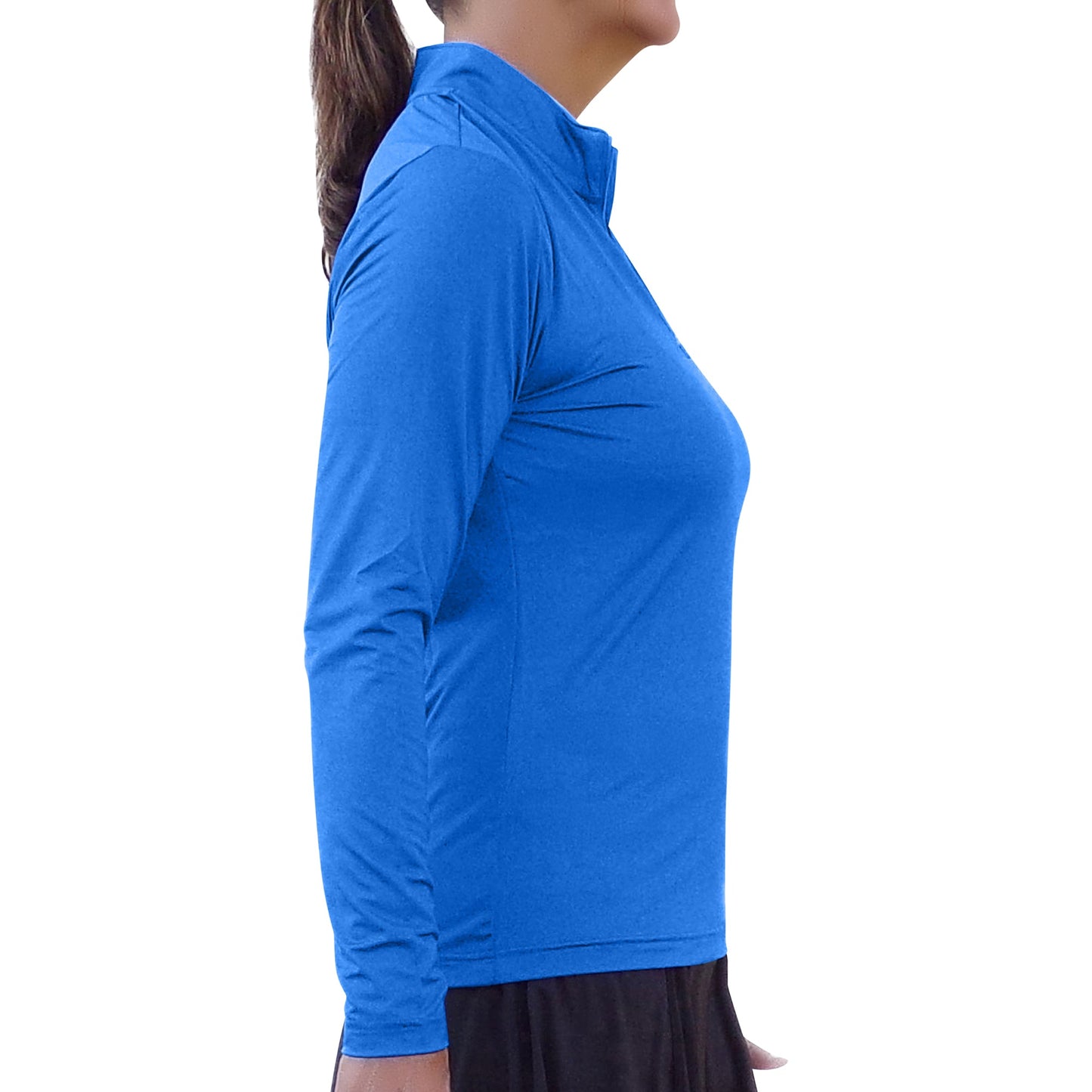 A woman in profile stands against a white background wearing the Pickleball Bella PB 1/4 Zip Long Sleeve Royal Blue top with SPF 50+ UV protection and a black skirt. Her brown hair is tied back in a ponytail, with her arms relaxed at her sides.