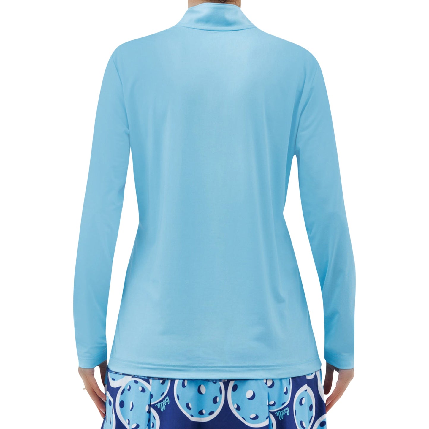 A person stands facing away in the Pickleball Bella PB 1/4 Zip Long Sleeve Sky Blue shirt, paired with a dark blue pickleball-patterned skirt. The breathable, moisture-wicking outfit offers comfort against a plain white background.