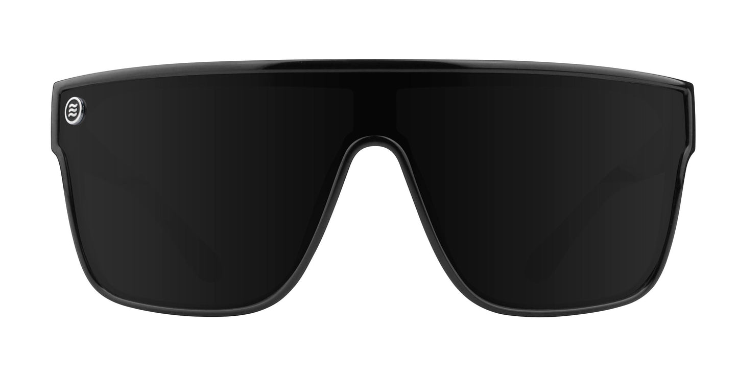 Front view of Neven Eyewear Wire oversized black sunglasses, featuring a single dark impact-resistant polarized UV400 lens, thick black frame, and a small circular silver logo on the upper left. Plain white background.