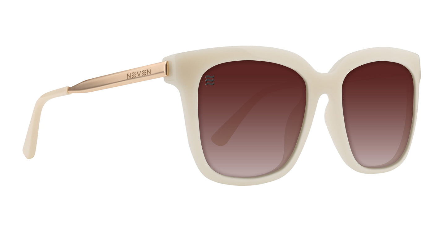 The Sand Dollar by Neven Eyewear features thick cream plastic frames, large square brown gradient lenses, and gold metallic arms engraved with NEVEN. A subtle wave logo inside adds a high-end touch to these stylish sunglasses.