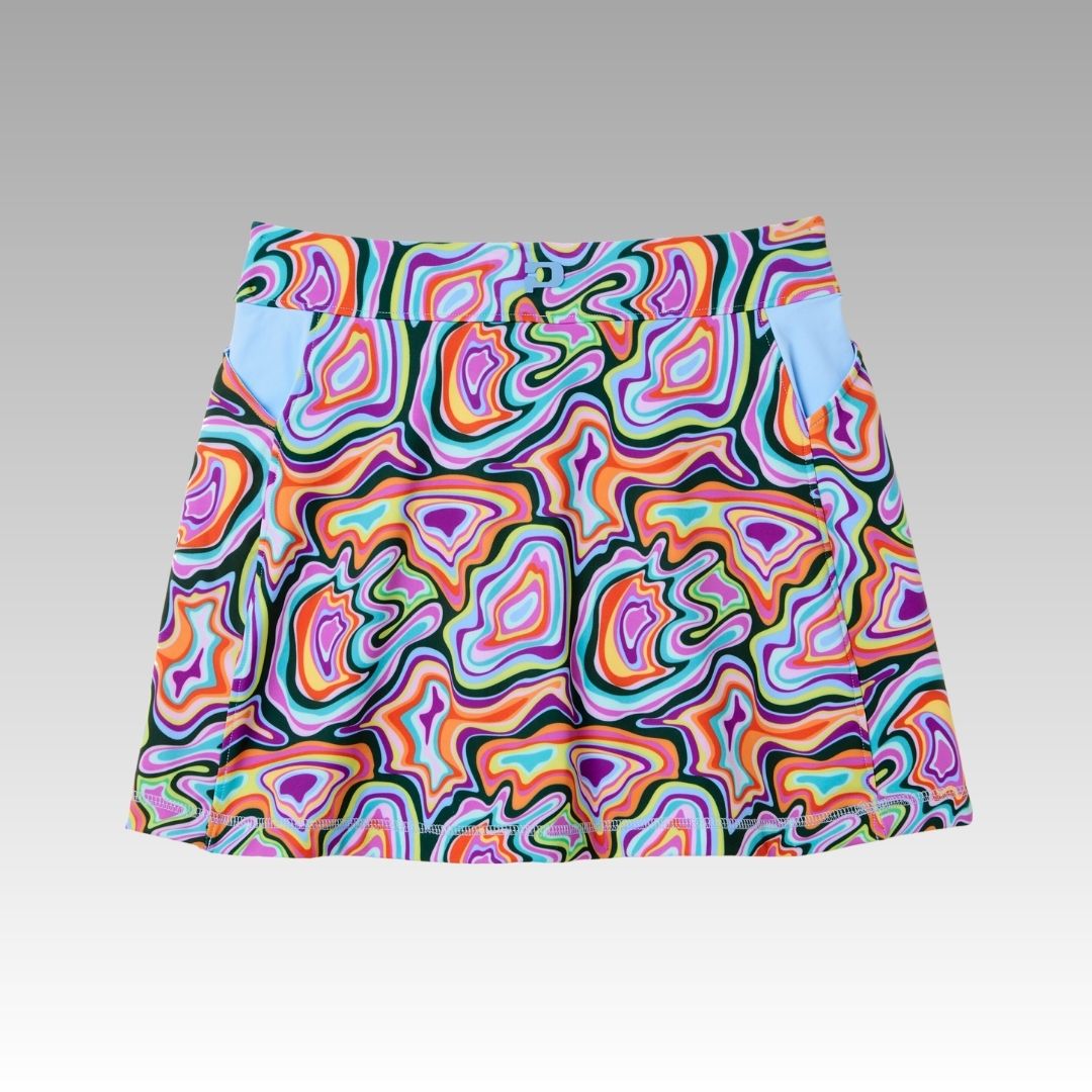 The Playly Store Sammy Skort is a colorful, knee-length pickleball skort featuring a bold wavy psychedelic pattern in purple, orange, green, blue, and pink. Made with SofKnit fabric, it has a fitted waistband and light blue-accented side pockets.