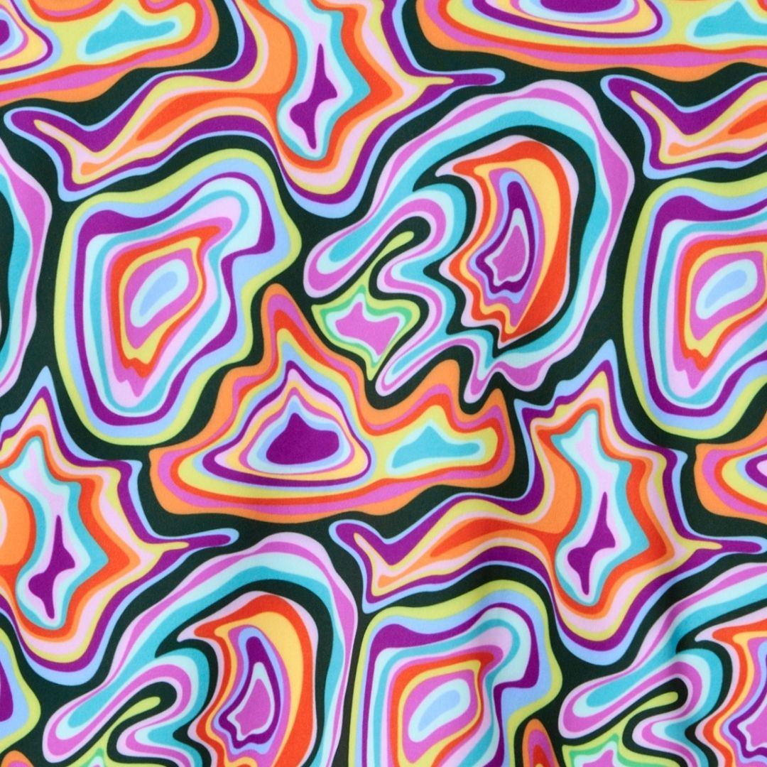 The Sammy Skort by Playly Store features a vivid abstract pattern of swirling, concentric shapes in bright colors with black outlines, printed on soft, moisture-wicking SofKnit fabric—perfect for stylish comfort on the pickleball court.