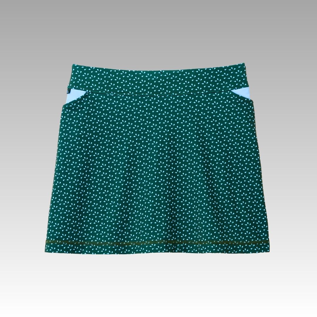 The Playly Store Sammy Skort features green SofKnit fabric with white polka dots, an A-line shape, two white triangle pockets by the waistband, and moisture-wicking comfort—ideal for pickleball. Shown on a gray gradient background.