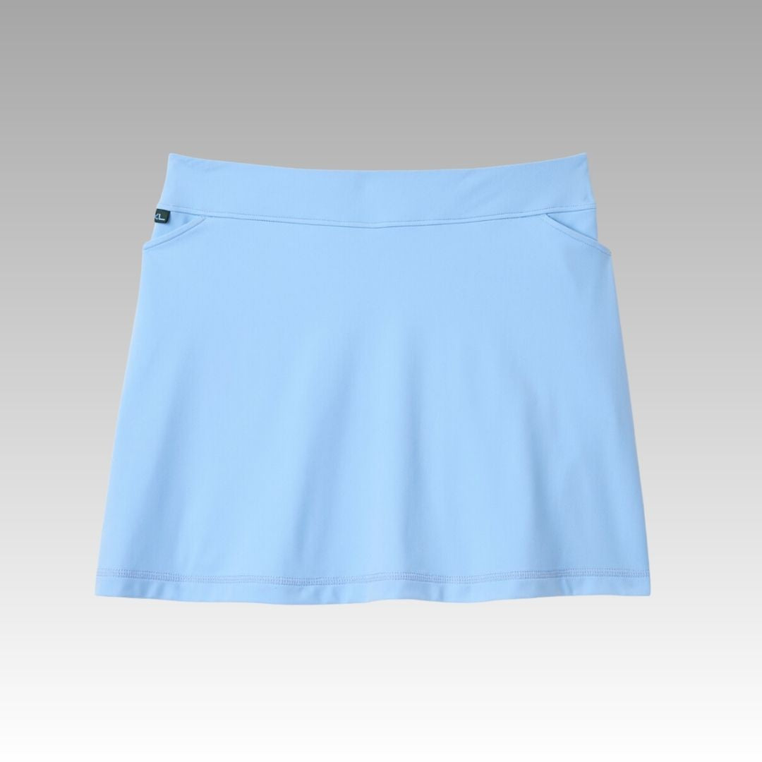 The Playly Store Sammy Skort is a light blue A-line pickleball skort with a wide waistband and subtle front pockets, made from moisture-wicking SofKnit fabric. Displayed on a grey-to-white gradient, it has clean lines and a small black tag by the waistband.