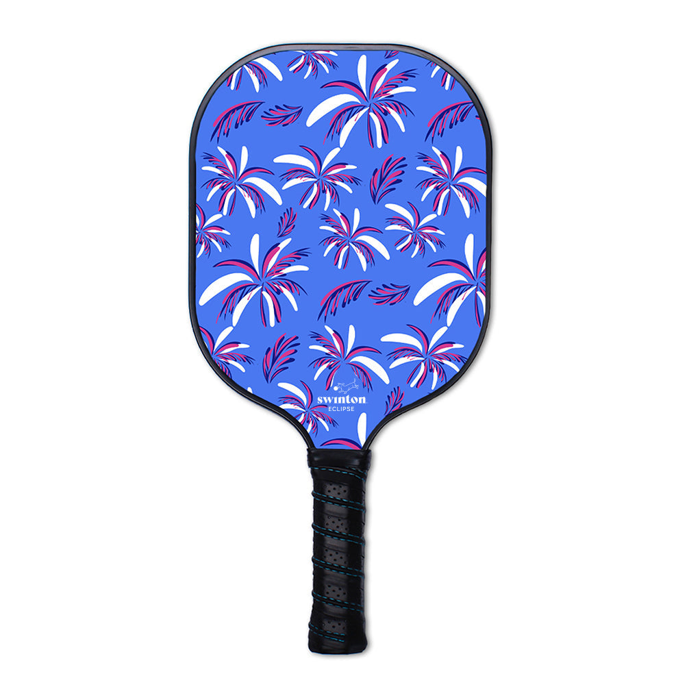 The Eclipse Island Vibes Pickleball Paddle by Swinton Pickleball features a blue graphite face with black grip, decorated with white, pink, and purple palm leaves. The Swinton logo appears near the bottom on a plain white background.