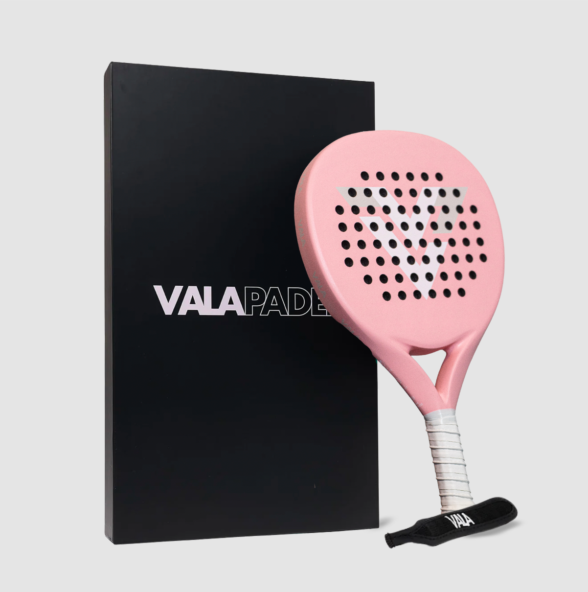 The VALA One (Pink Edition) padel racquet features a light pink design with a white grip, black vents, an EVA foam core, and a bold "V." It rests against a black box displaying the VALA logo—a standout for premium play.