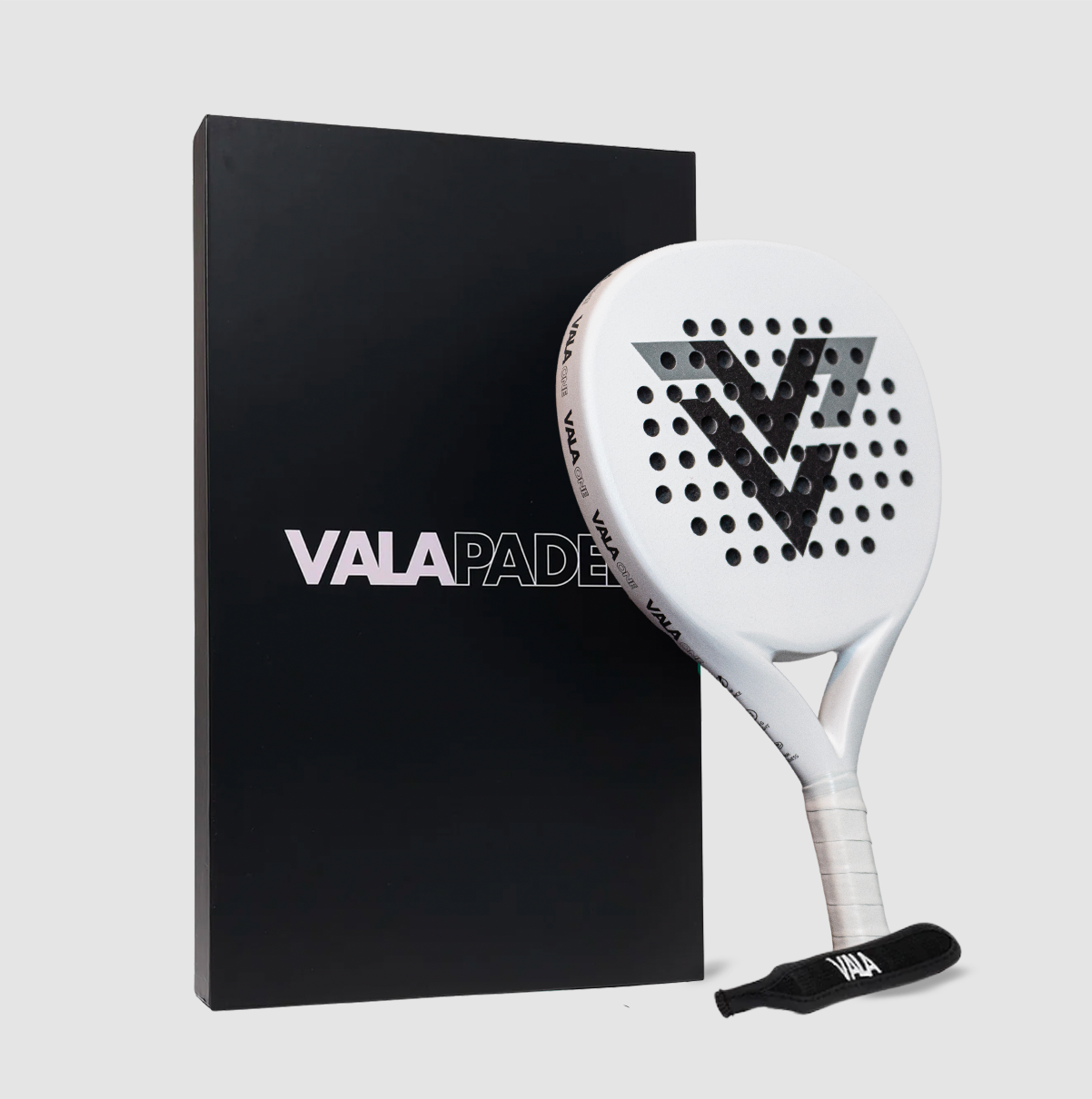 The VALA One (White Edition) padel racquet by VALA, featuring a black geometric V logo and white grip tape, is displayed against a sleek black VALAPADEL box in a minimalist setting on a light gray background.