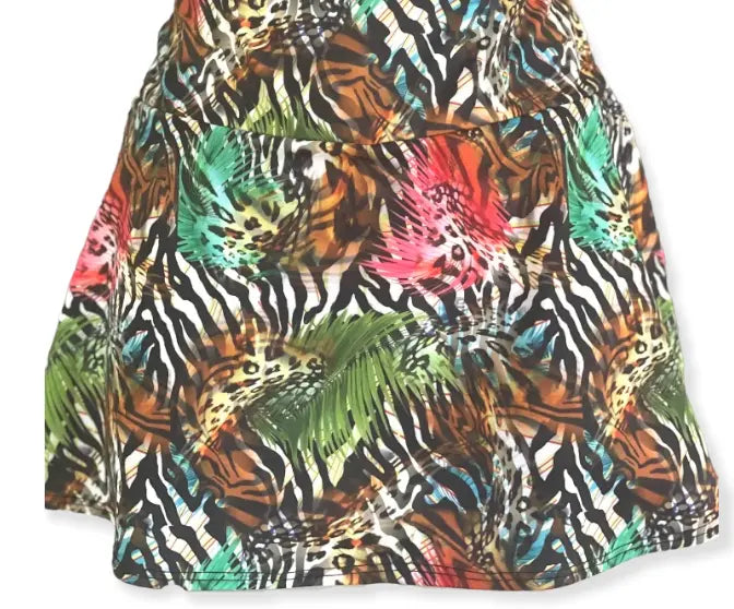 The Nola Go Wild Court Skirt by Runway Athletics showcases a bold animal print with zebra, leopard, and tiger patterns in green, turquoise, red, and orange. Only the lower half is shown; features a moisture-wicking under-short for comfort.
