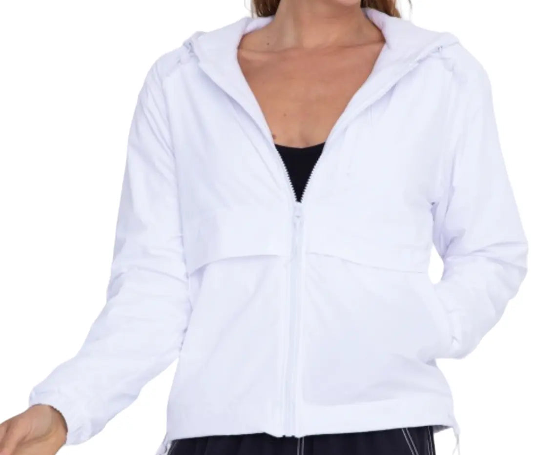 A woman wears the Runway Athletics Court Jacket—a white, zip-up hooded jacket with long sleeves, a relaxed fit, and side pockets—over a black top. She stands against a plain background, her right hand in her pocket and left arm bent.