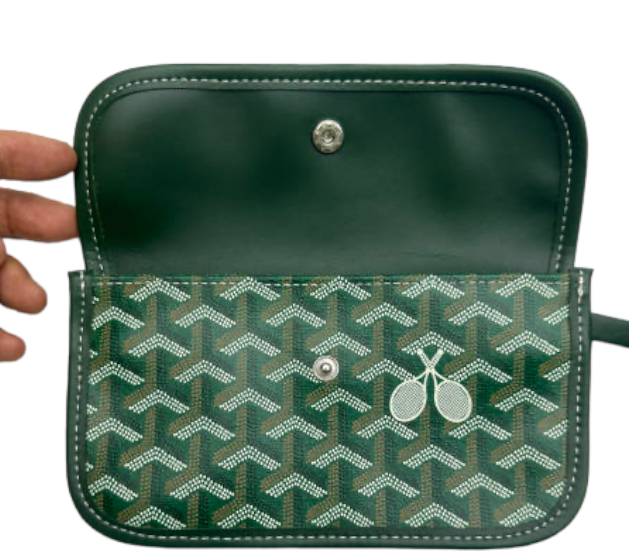 A hand holds open The Whimsy Tennis Lovers Large Tote - Green by Runway Athletics, featuring recycled hemp canvas, a silver snap button, a green geometric pattern with two white tennis rackets, and a plain dark green interior.