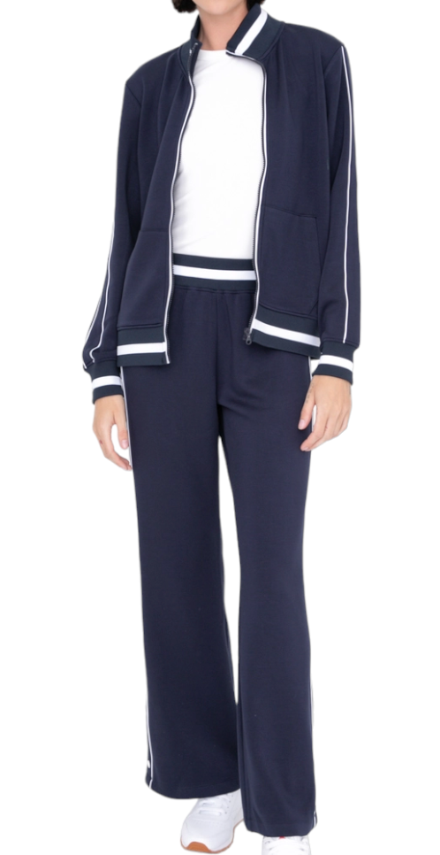A model wears the Runway Athletics Retro Vibe Tennis Tracksuit in navy with white trim, zip front, and pockets, styled with a white top and sneakers. The photo is cropped above the chin on a clean white background.