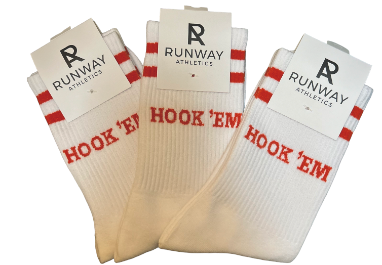 The Hook 'Em Socks by Runway Athletics are classic crew-length athletic socks in white, featuring red text for a comfortable and stylish look.