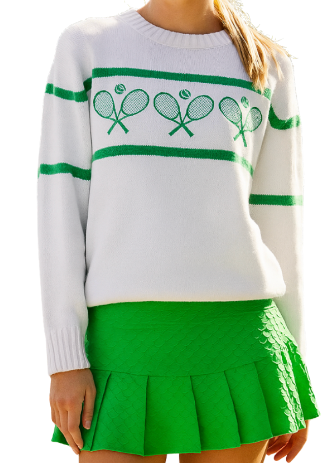 A person wears the Runway Athletics Tennis Racquets Sweater in cream/green, paired with a bright green pleated skirt. Their head is cropped out of the image, and their hair is tied back.