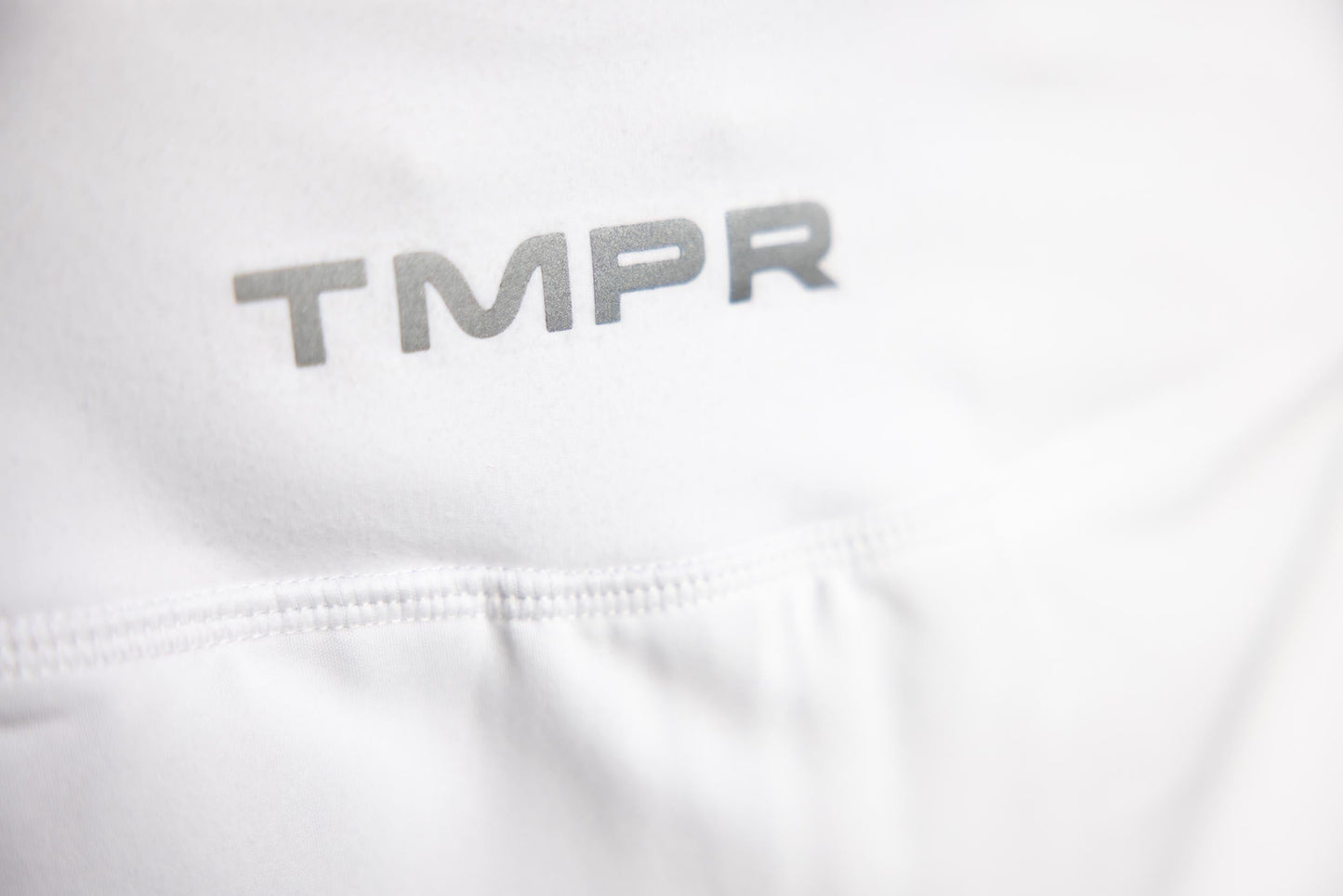 Close-up of the TMPR Performance Mid-Rise Skort by TMPR Sports, featuring smooth texture, detailed stitching, and "TMPR" in bold gray font on the top left. Fine seams highlight this women’s performance skort’s quality and design.