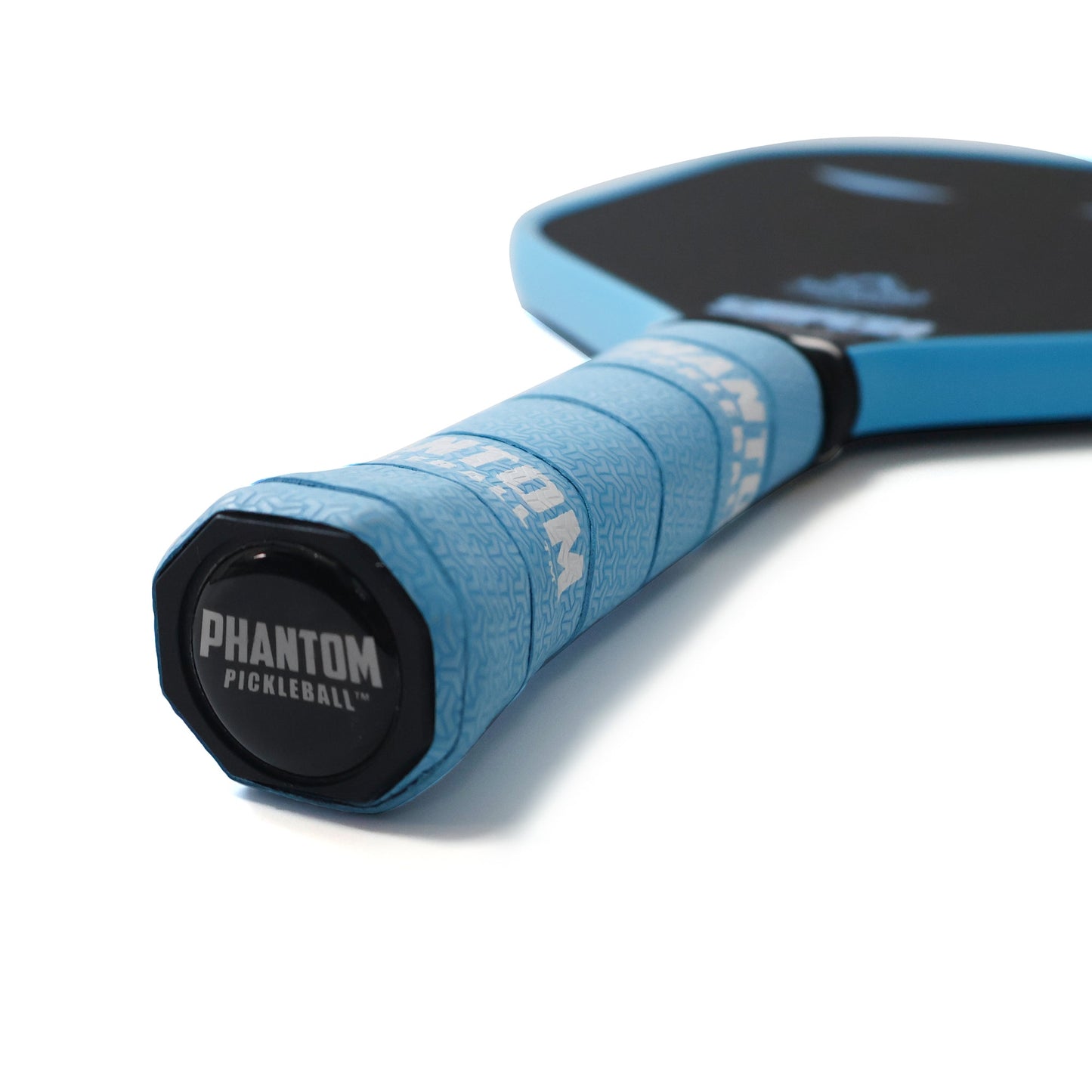 Close-up of a blue-handled PHANTOM SNIPER PRO 12MM T700 Raw Carbon Fiber Thermoformed Pro Pickleball Paddle by Phantom Pickleball, showing its textured grip, black cap with logo, and part of its advanced carbon surface and edge.