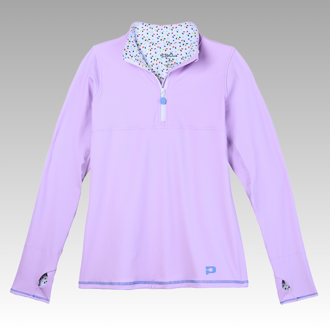 The Soleil Tech Shirt from Playly Store is a light purple, long-sleeved athletic pullover with a half-zip, breathable fabric, thumbhole cuffs with black accents, a white inner collar with colorful dots, and a blue logo on the hem.
