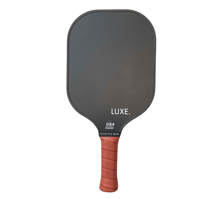 The Core Collection paddle from LUXE Pickleball features a matte black carbon fiber face labeled “LUXE.” and “USA Pickleball Approved” near the handle, with a textured reddish-brown grip, shown on a plain white background.