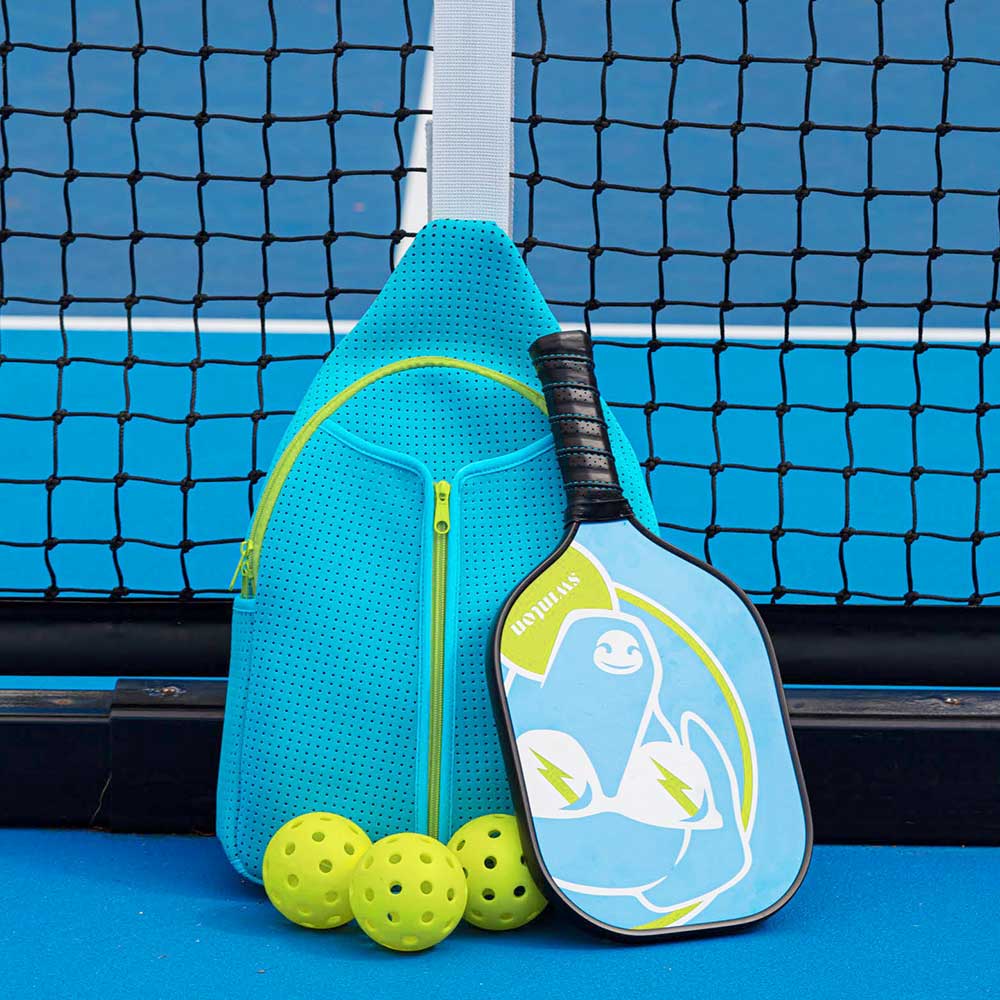 The Swinton Pickleball Starter Bundle - Blue includes a blue paddle with penguin graphic, three yellow balls, and a blue zippered bag—perfect for beginners on the court or as a fun pickleball gift.