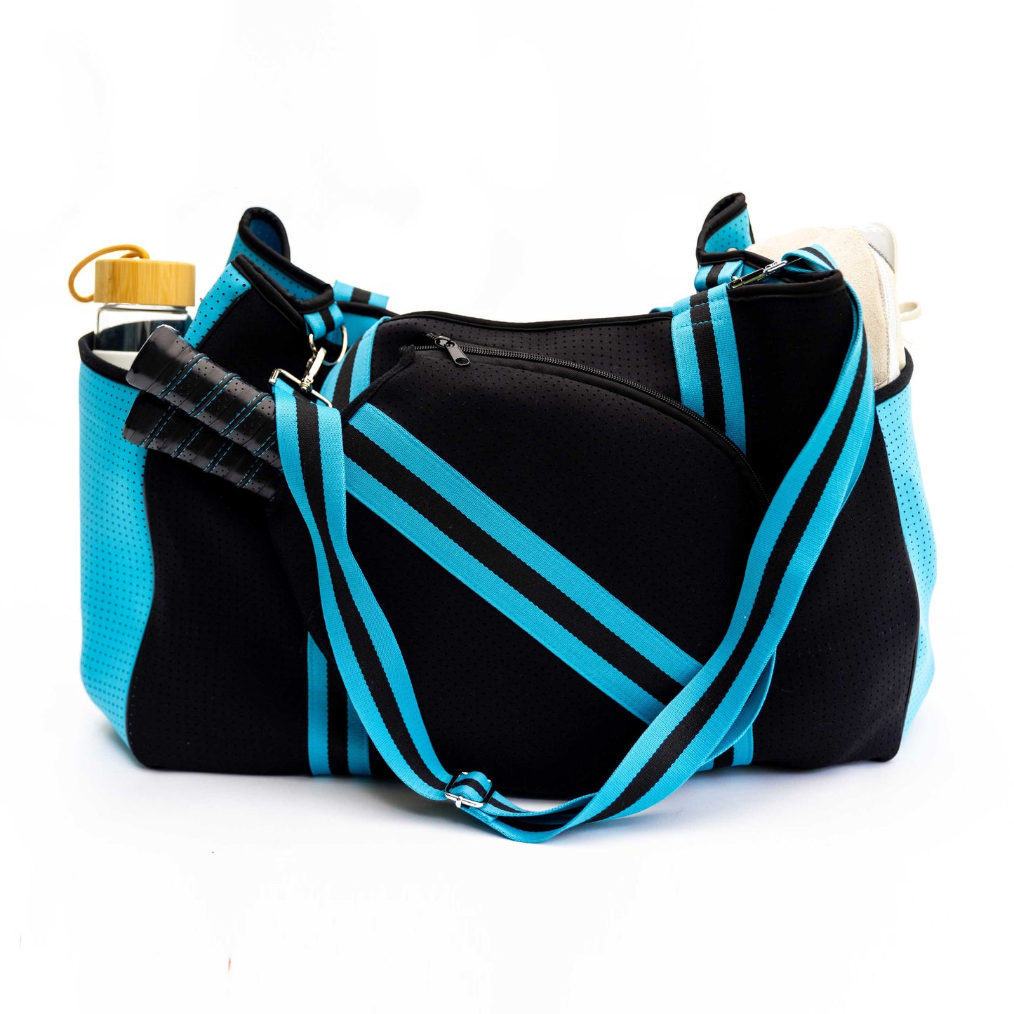 The Swinton Pickleball XL Pickleball Tote Bag in black features bright blue stripes and a shoulder strap, shown against a white background with side pockets holding a beige towel, gold water bottle, and black-handled jump ropes draped over the front.