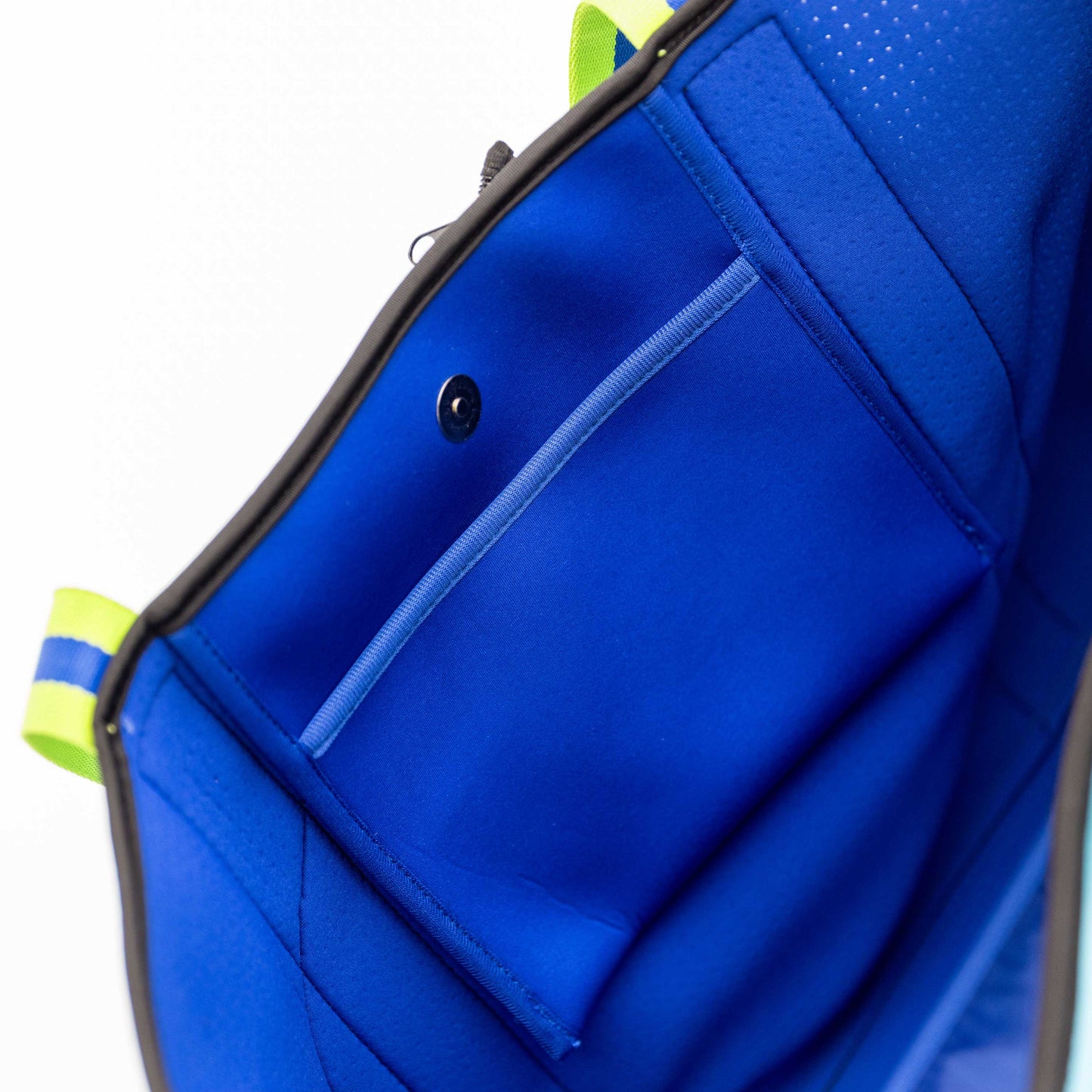 Close-up of the Swinton Pickleball XL Pickleball Tote Bag - Blue, featuring neoprene material, a snap button, inner pocket, light blue accent trim, neon yellow handle, blue-striped loop, and soft padding against a white background.