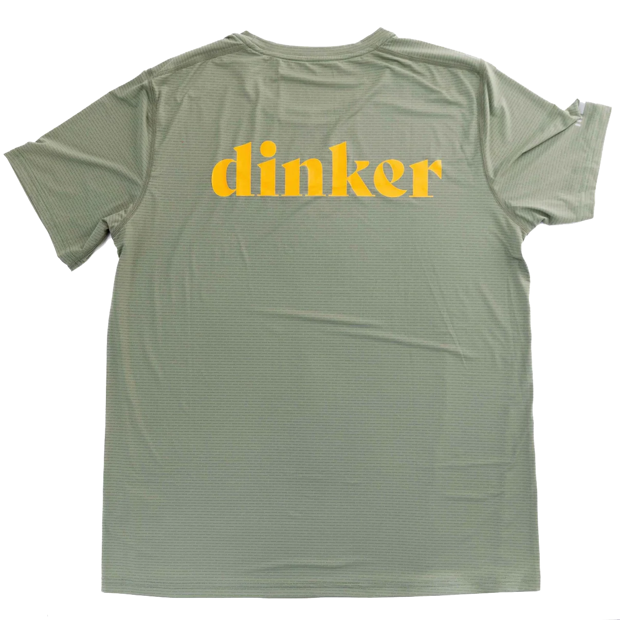 The Women's Dinker LUX Performance Shirt by Swinton Pickleball is shown flat from the back, featuring “Dinker” in bold yellow across the upper back. This light green shirt offers a subtle striped texture, relaxed fit, and performance material.