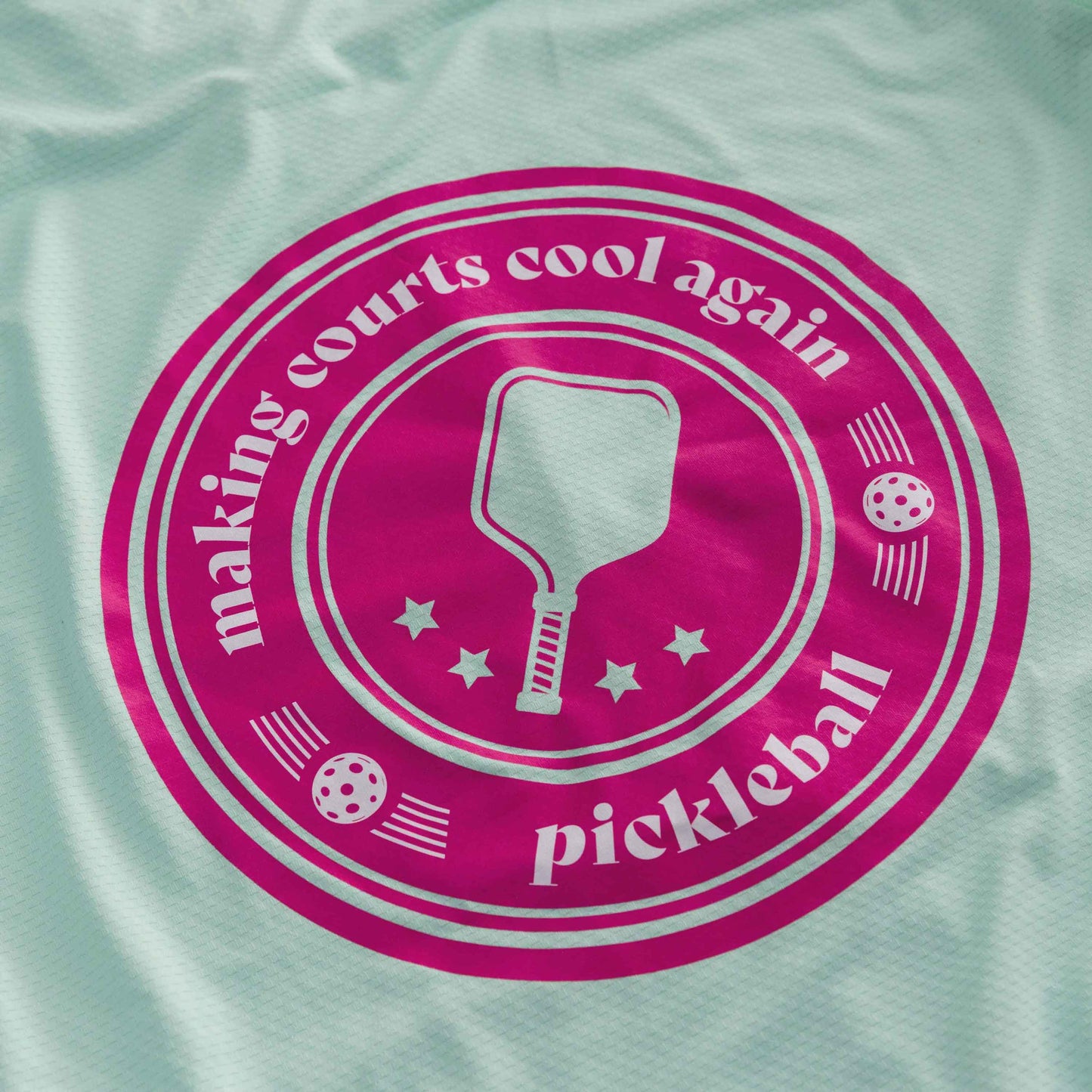 A pink circular logo with “making courts cool again pickleball,” paddle, stars, and three pickleballs decorates this lightweight, breathable Mint Zip-Front Sun Hoodie by Swinton Pickleball—complete with UPF 50+ sun protection.
