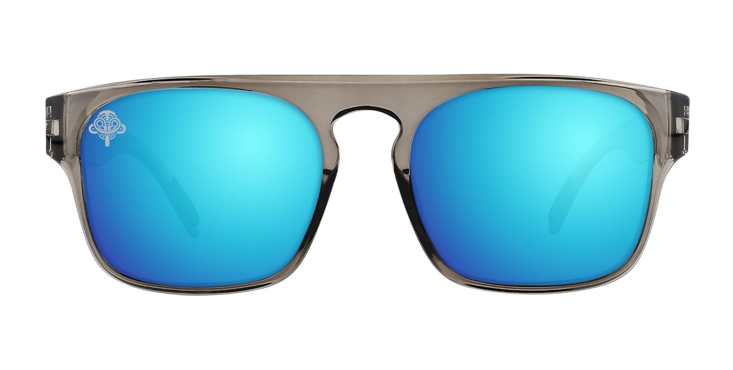 The Neven Eyewear Wubula sunglasses feature polarized, bright blue mirrored lenses, translucent gray frames, a bold straight brow line, wide temples, and a white Dirt Monkey logo on the left lens.
