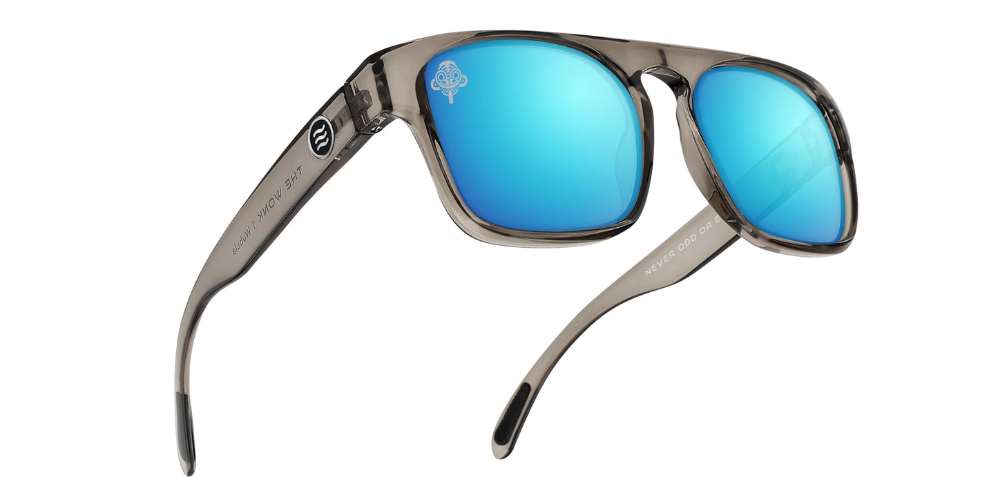 The Wubula by Neven Eyewear features translucent gray frames, shiny blue mirrored polarized lenses with a white tree logo, slightly curved arms with black tips, and “NEVER DROP, NEVER LOSE” printed inside the right arm.