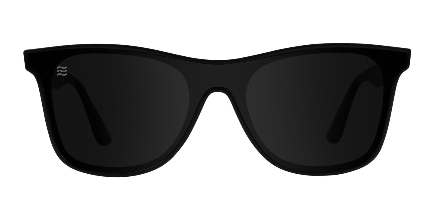 The Neven Eyewear Goblin sunglasses feature a classic rectangular frame, black polarized UV400 lenses, and a small wavy logo on the left lens. Simple and modern, they're shown front-facing against a white background.