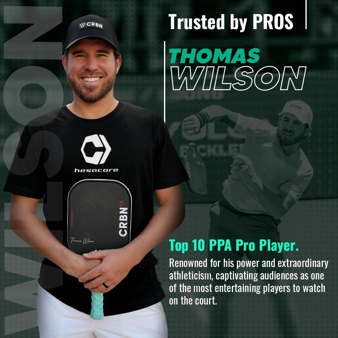 A smiling man in a black cap and t-shirt holds a paddle with the Hesacore Grip Pickleball Grip - 5.25 Inches Long, Regular Feel, White. Text: “Trusted by PRO THOMAS WILSON—Top 10 PPA Pro renowned for power and sweat-absorbing grip.” Grayscale action background.