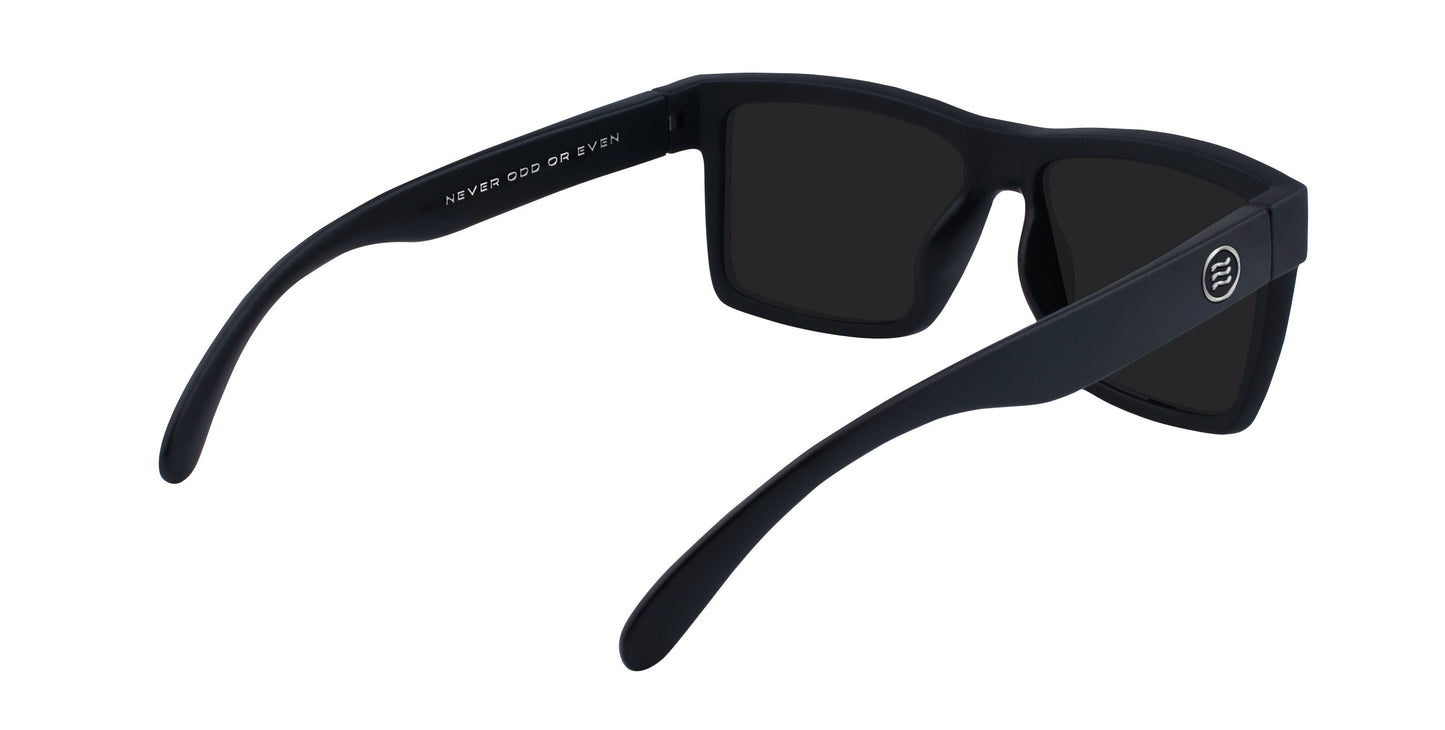 The Lowrider by Neven Eyewear is a black vintage motorcycle sunglass with dark lenses, wide arms, and a matte angular frame. The left arm displays "NEVER ODD OR EVEN" in white for a modern twist on classic gothic style.